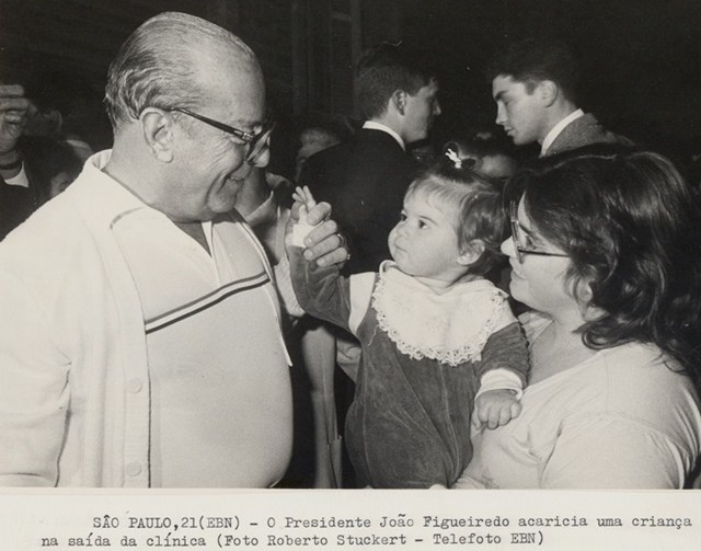 Presidente João Figueiredo acaricia uma criança na saída da clínica
