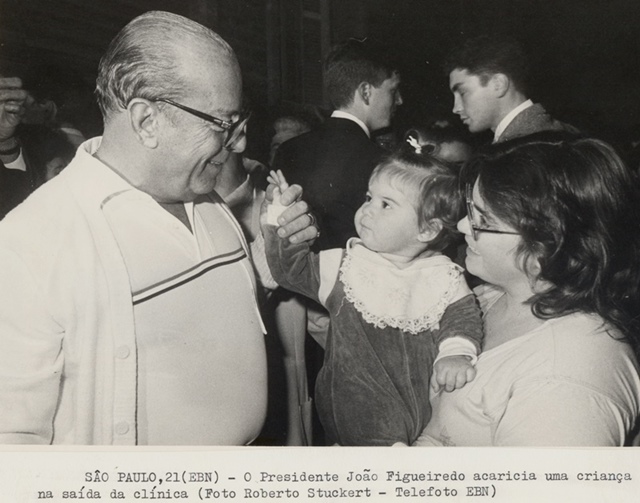 Presidente João Figueiredo acaricia uma criança na saída da clínica