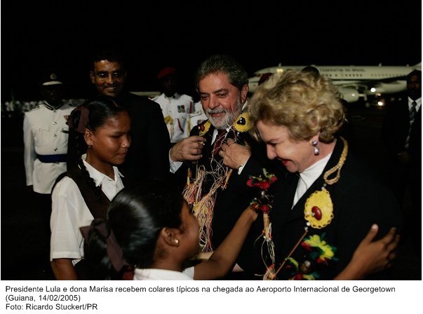 Presidente Lula e dona Marisa recebem colares típicos na chegada ao Aeroporto Internacional de Georgetown.