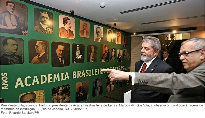 Presidente Lula, acompanhado do presidente da Academia Brasileira de Letras, Marcos Vinícios Vilaça, observa o mural com imagens de membros da instituição.