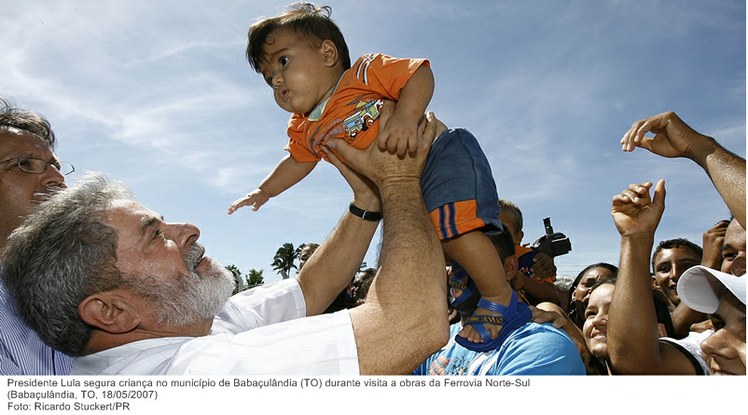 Presidente Lula segura criança no município de Babaçulândia (TO) durante visita a obras da Ferrovia Norte-Sul.