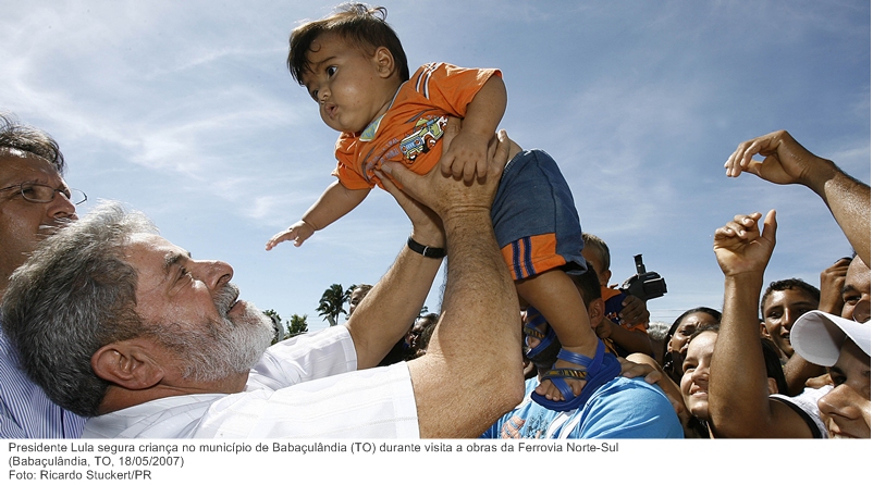 Presidente Lula segura criança no município de Babaçulândia (TO) durante visita a obras da Ferrovia Norte-Sul.