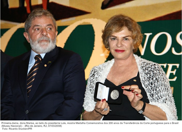 Primeira-dama, dona Marisa, ao lado do presidente Lula, mostra Medalha Comemorativa dos 200 anos da Transferência da Corte portuguesa para o Brasil (Museu Nacional).
